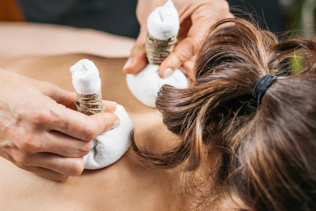 therapist applying herbal potli massage for pain relief in Bangalore